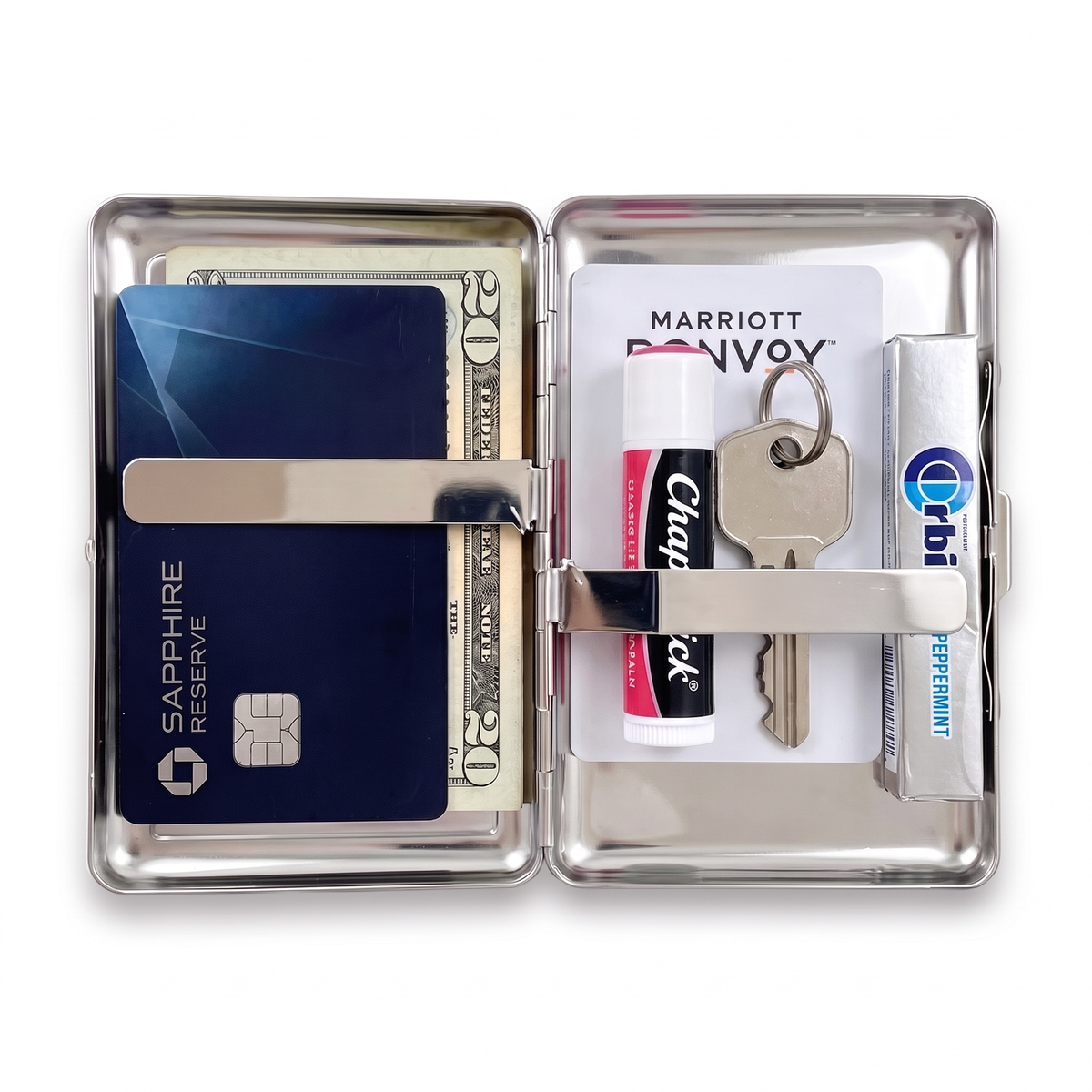 Tin cardholder wallet open, holding a metal card, cash, a hotel key card, lip balm, a key and gum